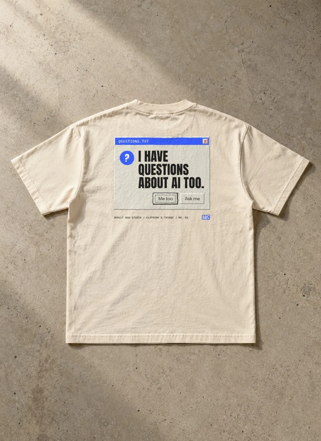 The questions tee laid flat on concrete, back side up.